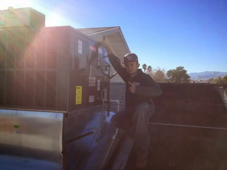 HVAC technician performing AC Tune-Up on a rooftop unit in Great Bend